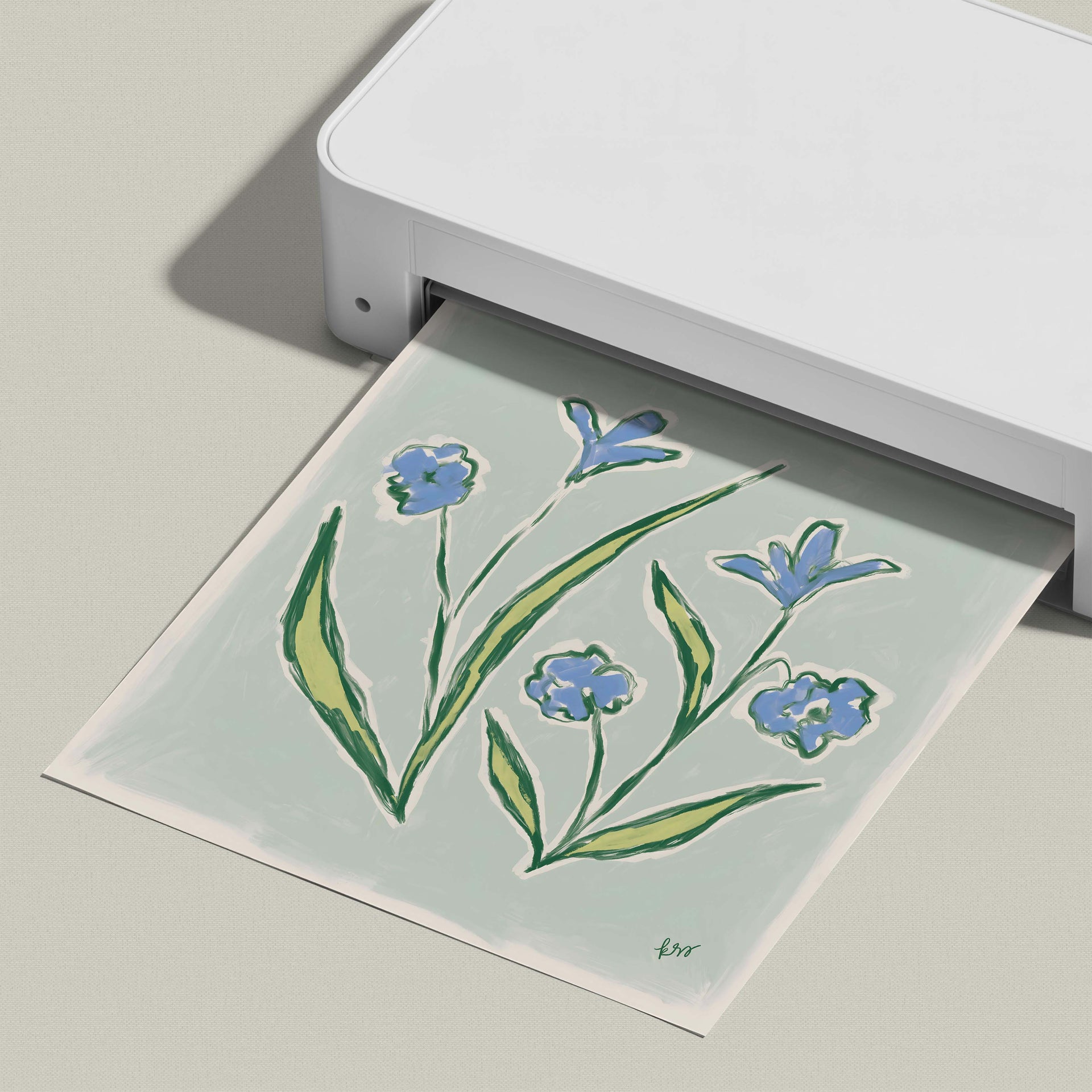 A white printer is printing a paper with a drawing of blue flowers on it.