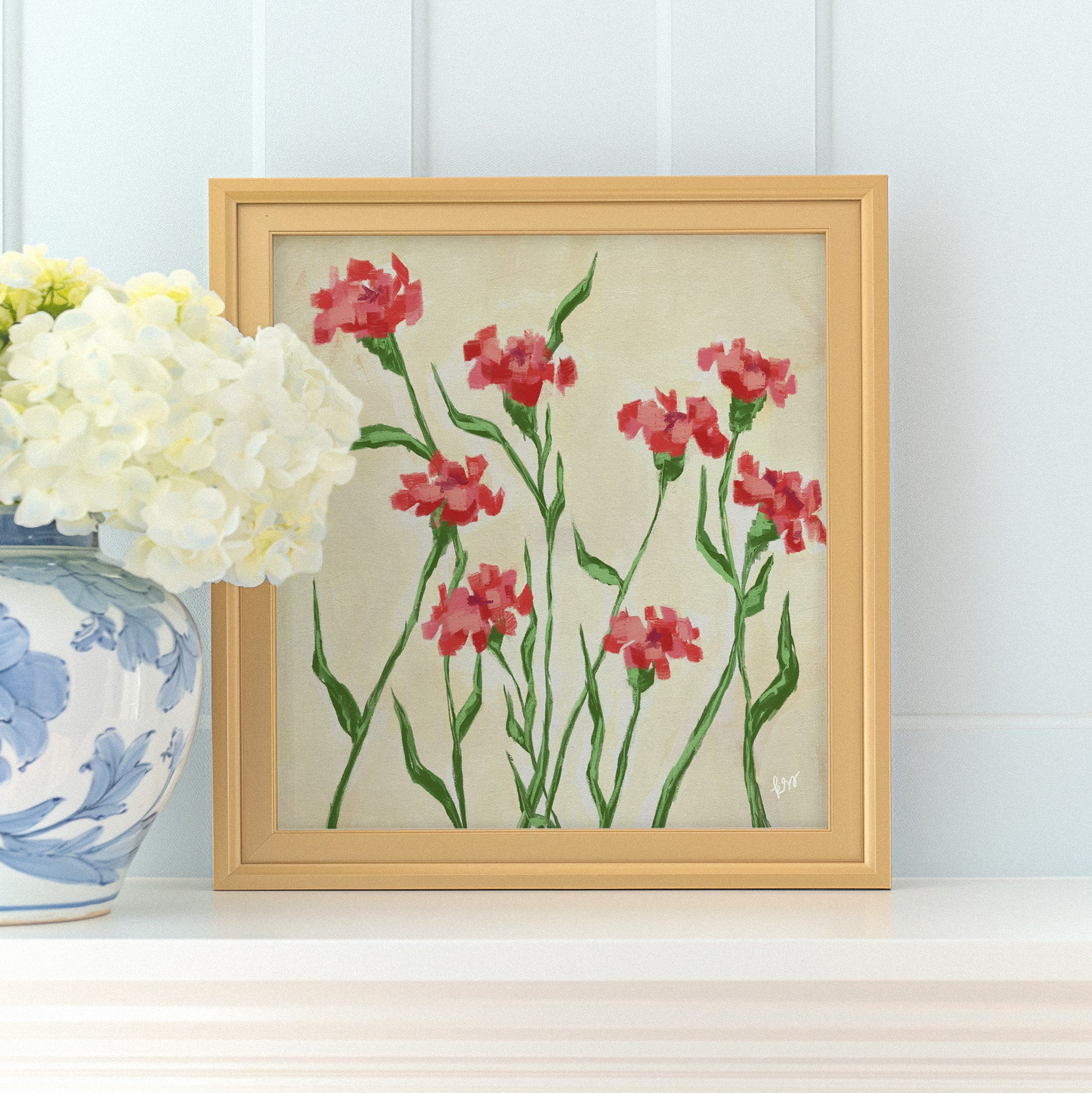 a framed painting of red flowers with green stems, placed on a white shelf next to a blue and white vase with white flowers.