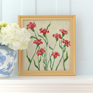a framed painting of red flowers with green stems, placed on a white shelf next to a blue and white vase with white flowers.