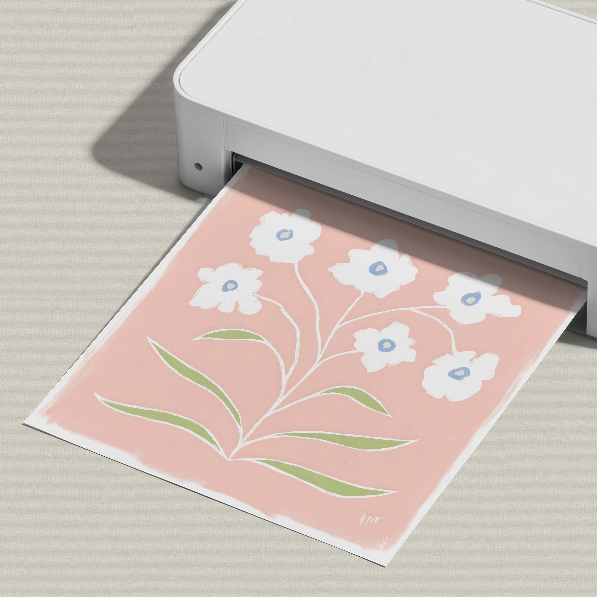 A white printer is printing a pink and white floral design on a piece of paper.