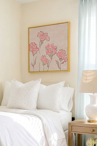 a bedroom with a bed, a nightstand, and a framed artwork of pink flowers on the wall.