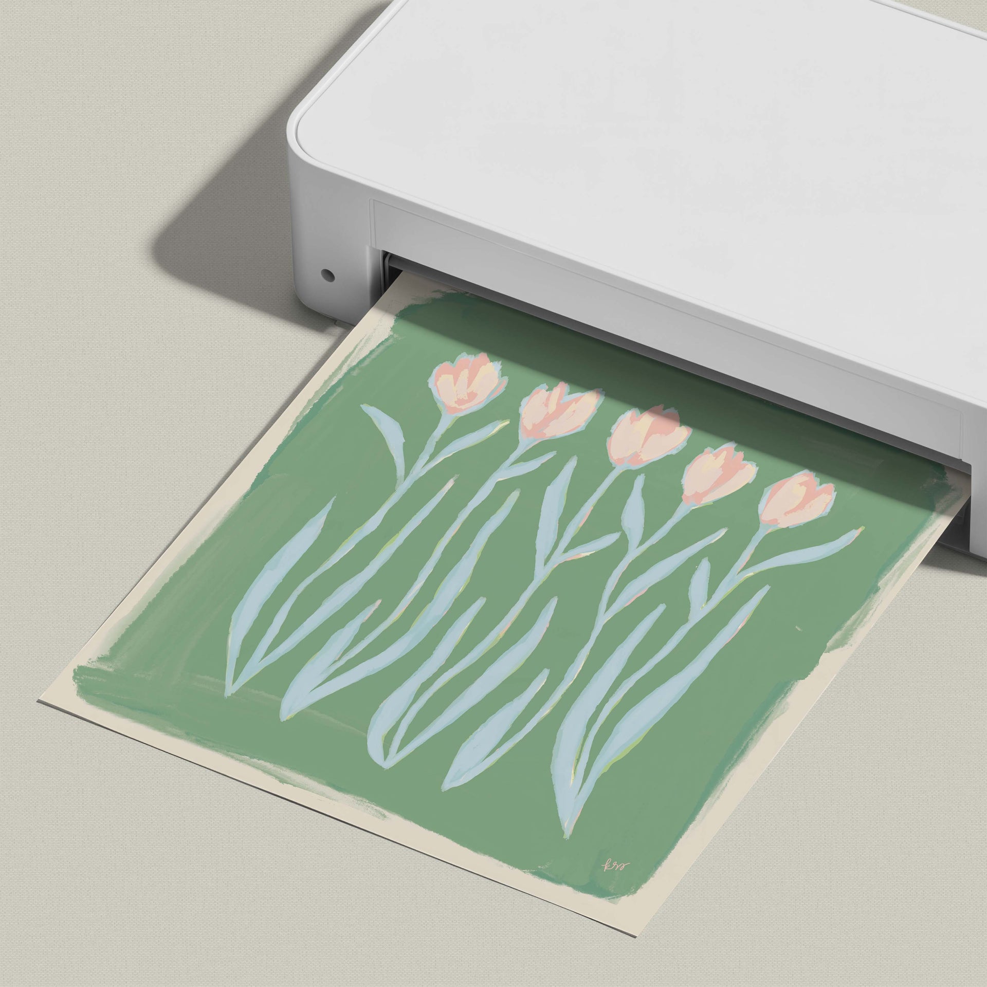A white printer is printing a green paper with a floral design of pink flowers.
