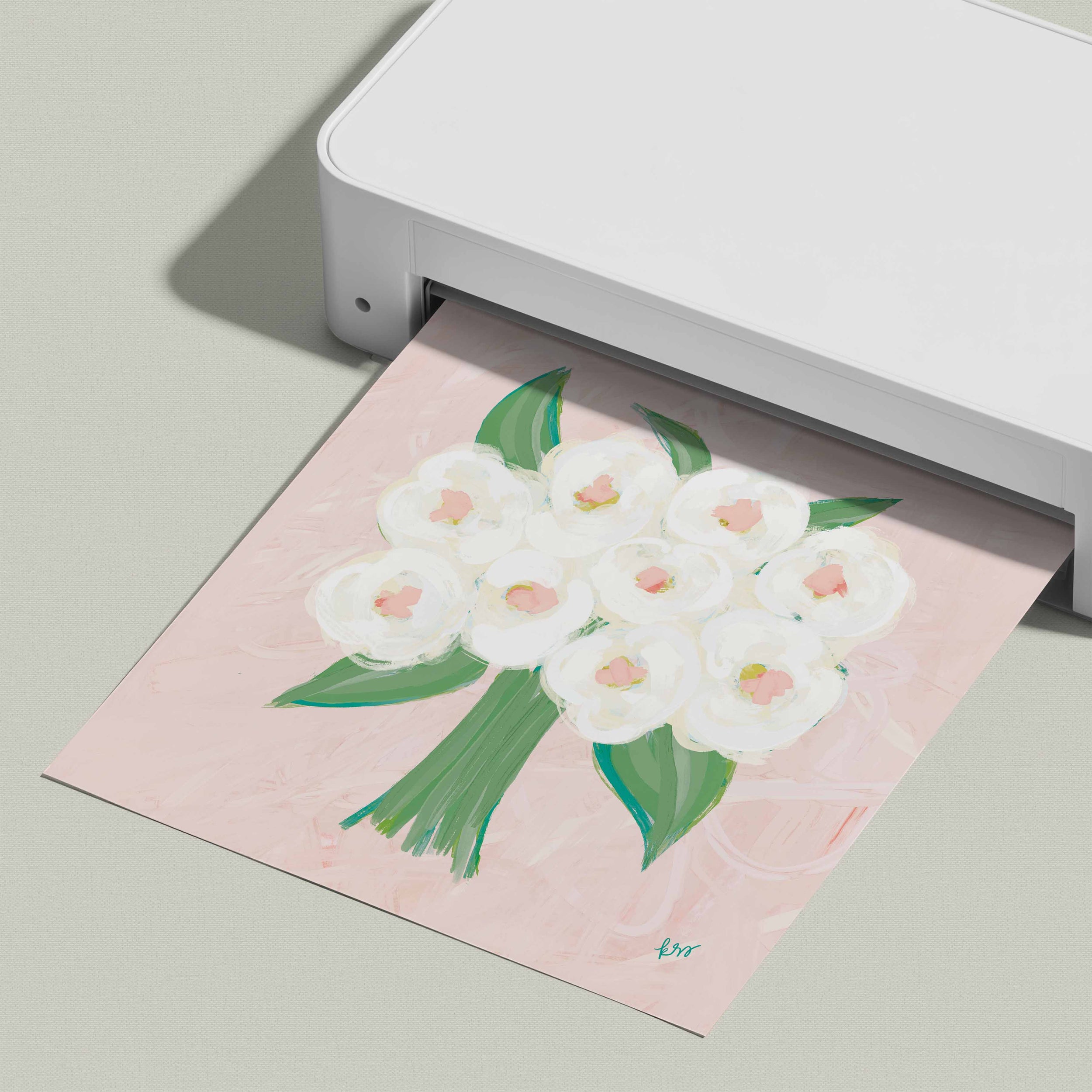 A white printer is printing a paper with a floral design featuring white flowers and green leaves.