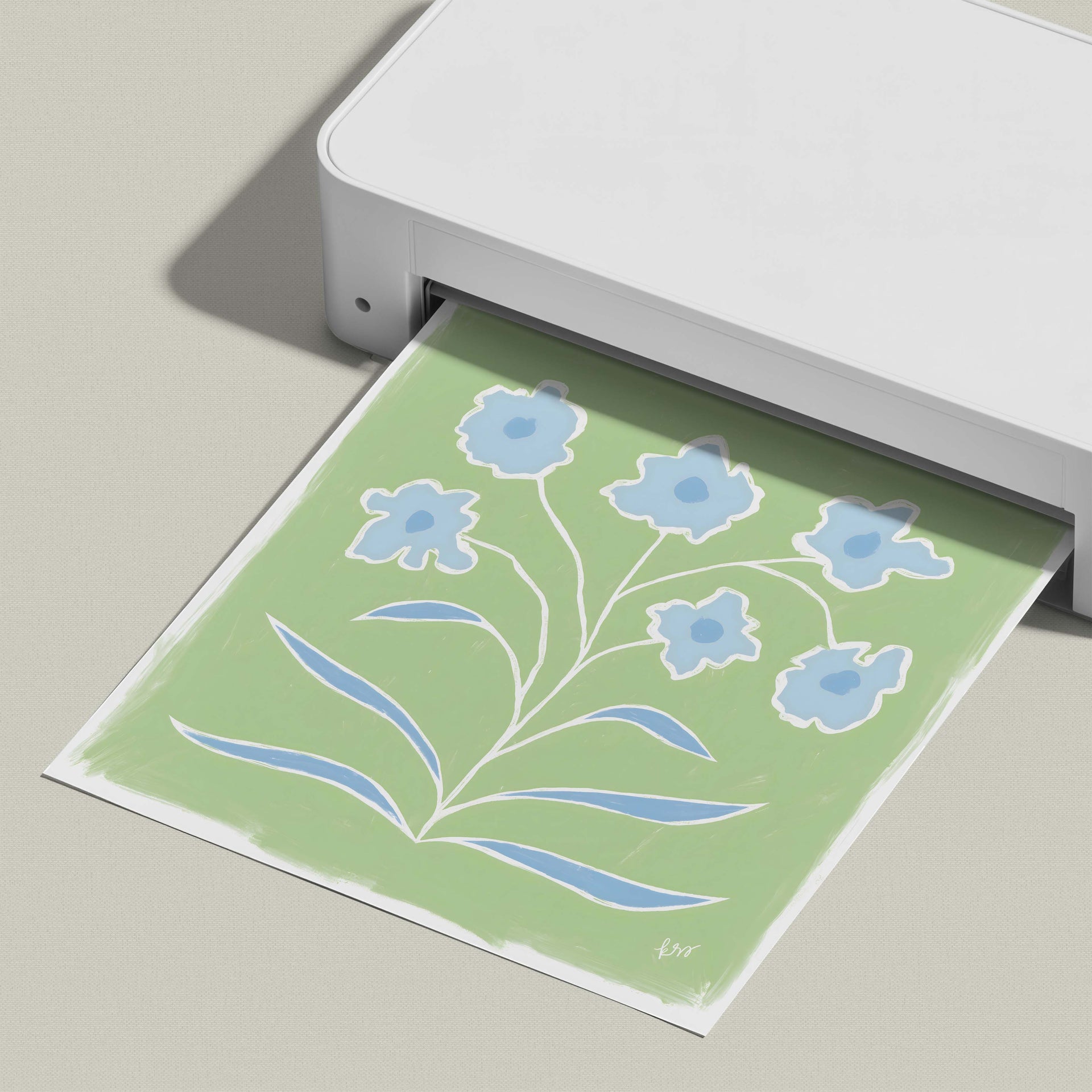 A white printer is printing a green and white floral design on a piece of paper.