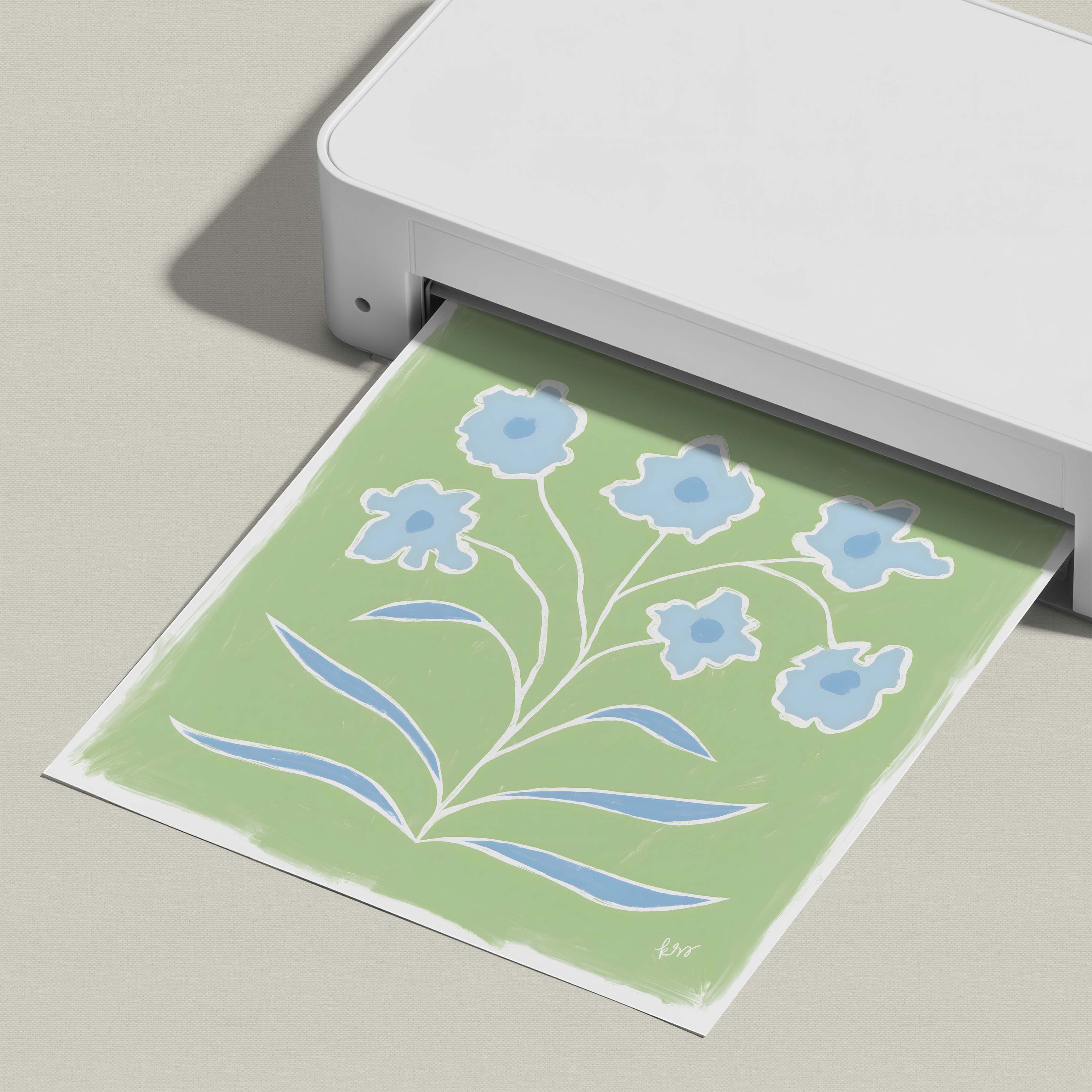 A white printer is printing a green and white floral design on a piece of paper.