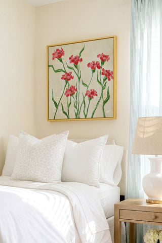 a serene bedroom scene with a bed adorned with white linens and a framed painting of red flowers hanging above it.