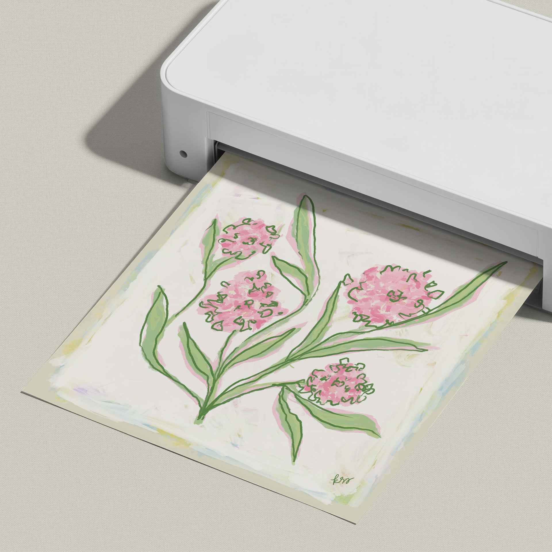 A white printer is displaying a printed image of a floral design with pink flowers and green leaves.
