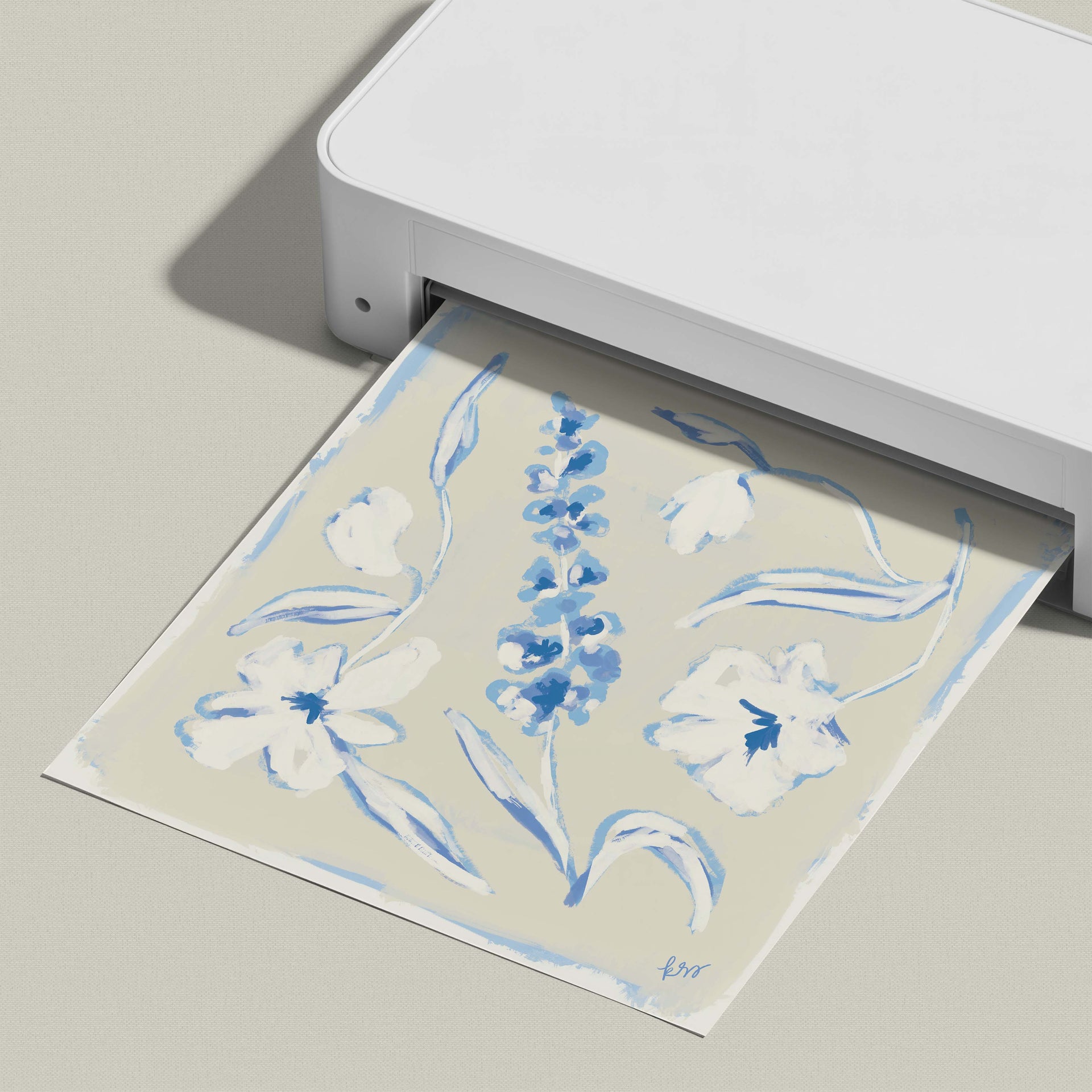 A white printer is printing a paper with a blue floral design on it.